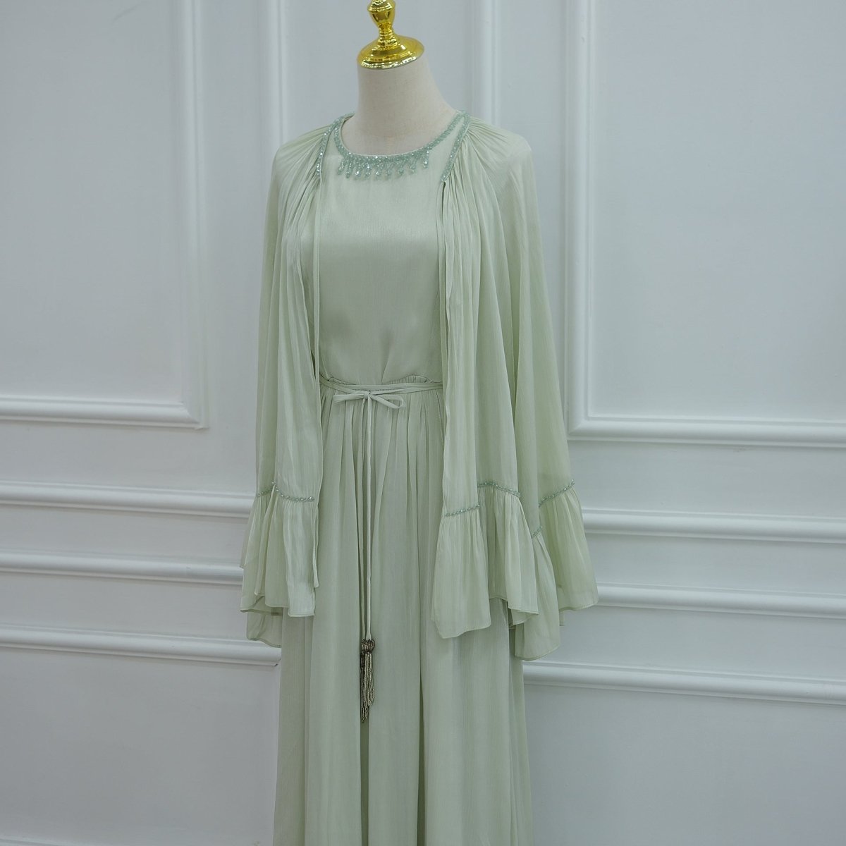 Model posed to show the graceful drape of the pleated skirt and cape hem