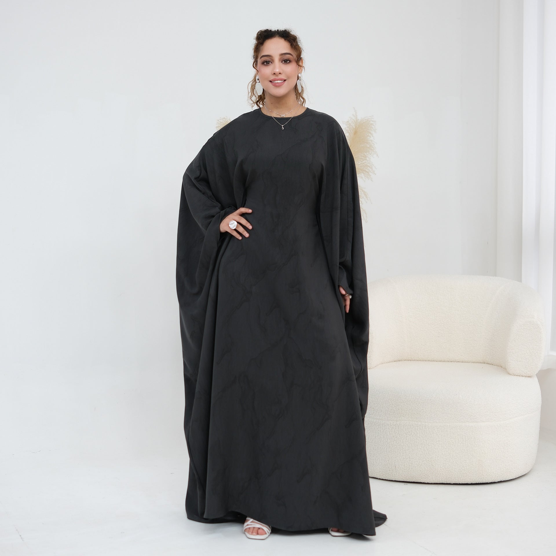 Arms raised showing full batwing sleeve sweep on gold print maxi dress