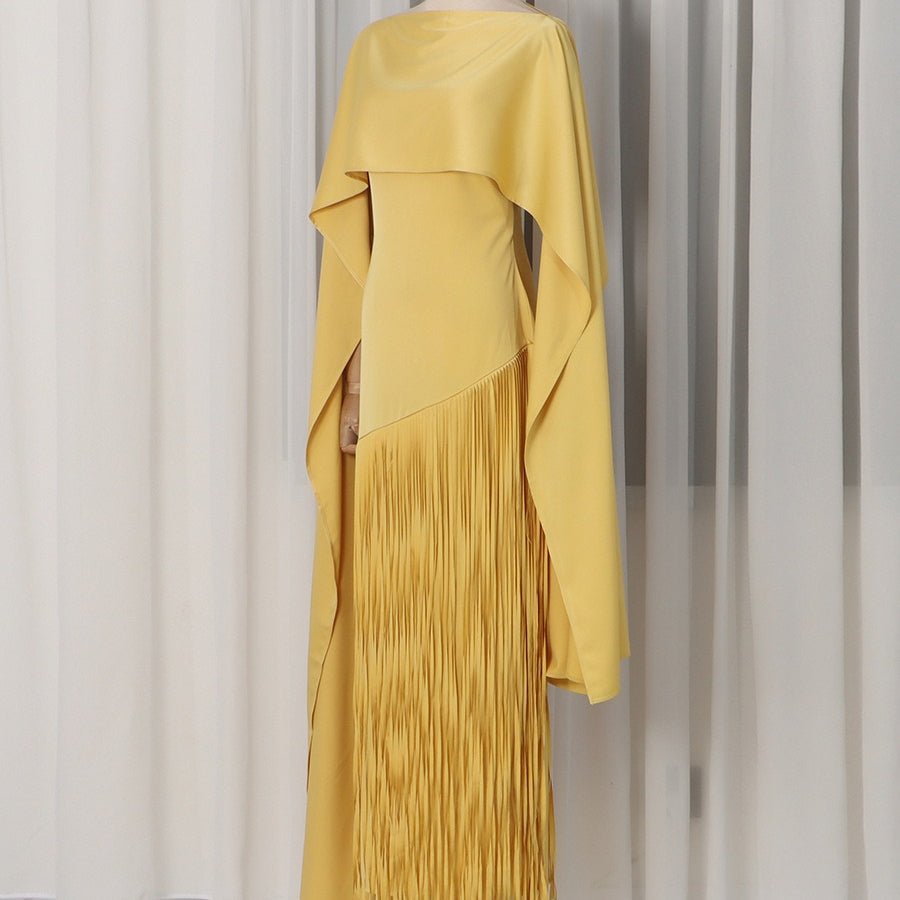 Shoulder cape draping over fitted sleeveless sheath dress in golden yellow