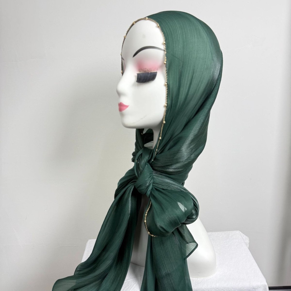 Overhead flat lay of gold chain beaded crinkle satin hijab in neutral tone