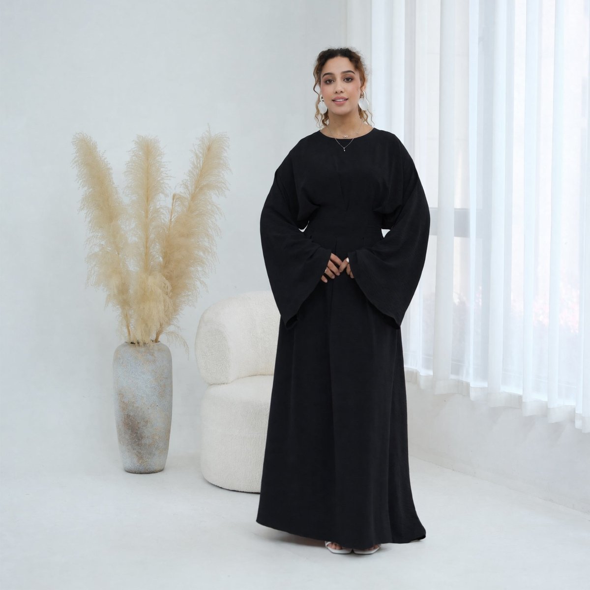Three-quarter view of batwing sleeve drape and cinched waist silhouette