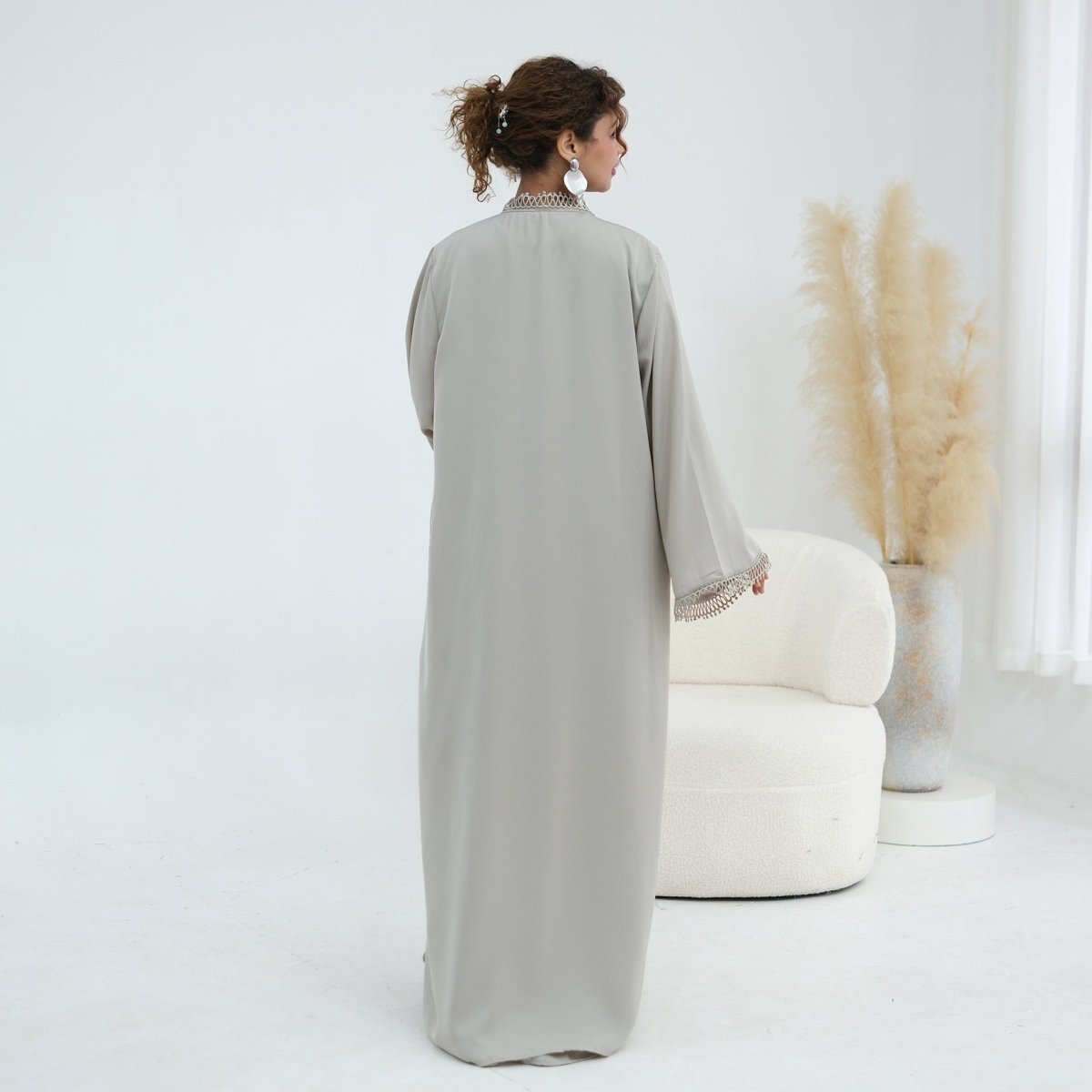 Model wearing lace abaya with inner dress in a formal setting