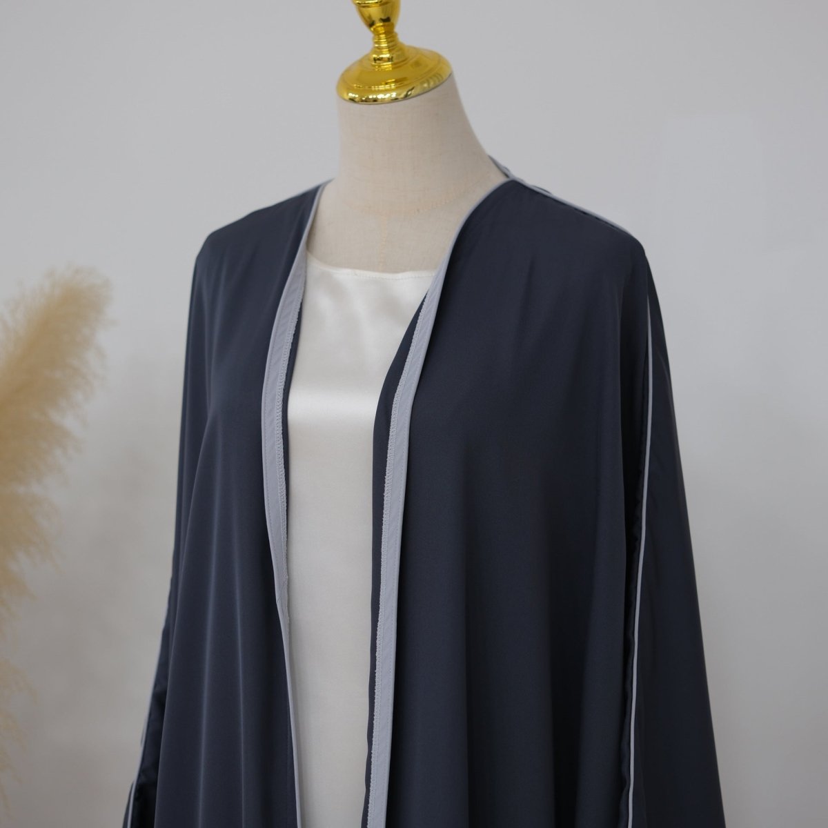Sleeve sweep detail of contrast piped batwing abaya from shoulder to wrist