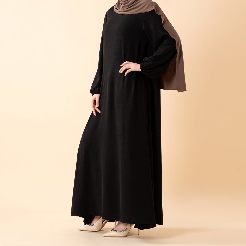 Essential Flow abaya shown in indoor natural light — opaque weave