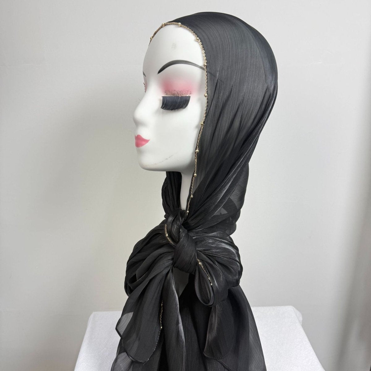 Hijab styled elegantly with gold chain edge detail visible at front