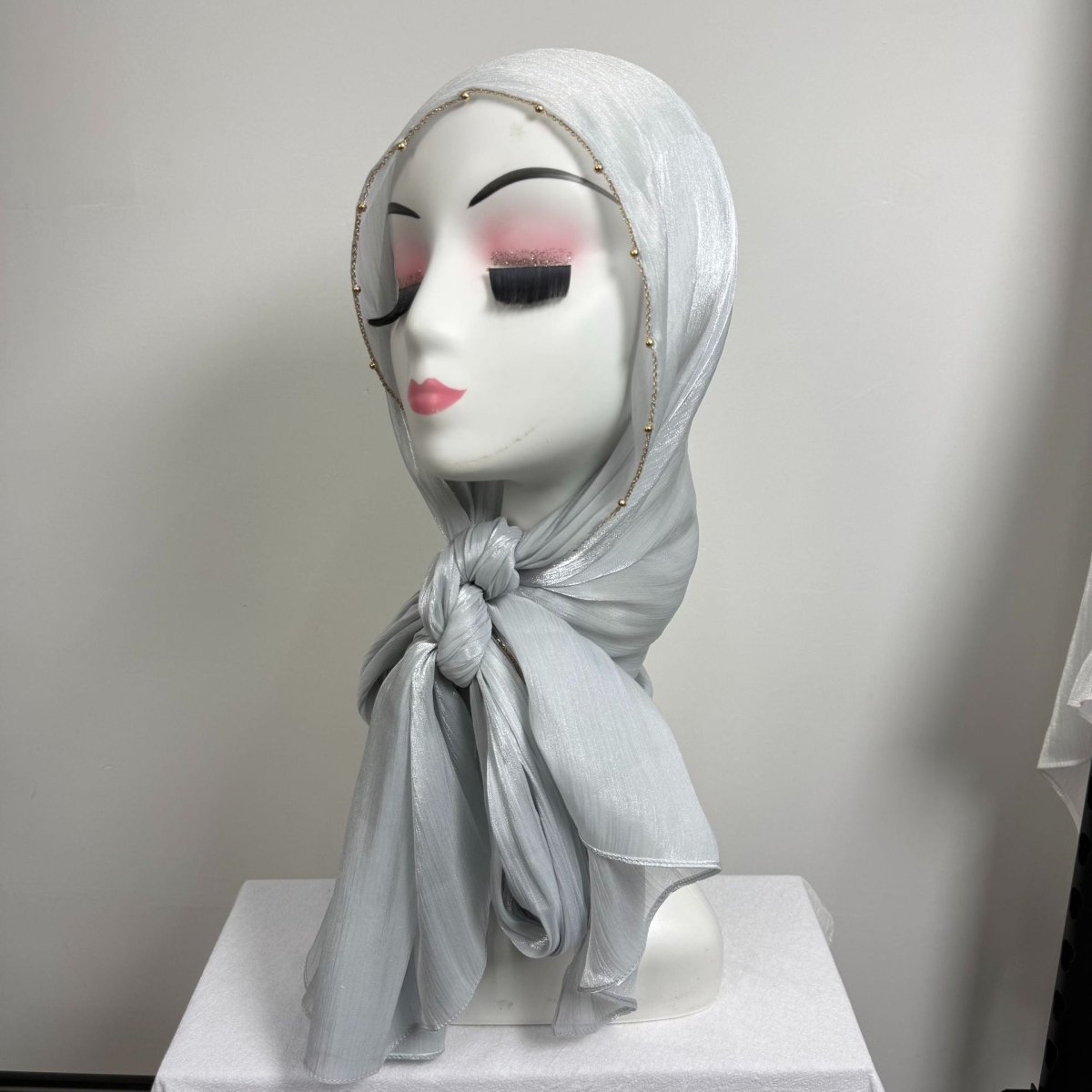 Front drape view of gold beaded edge satin hijab in muted tone