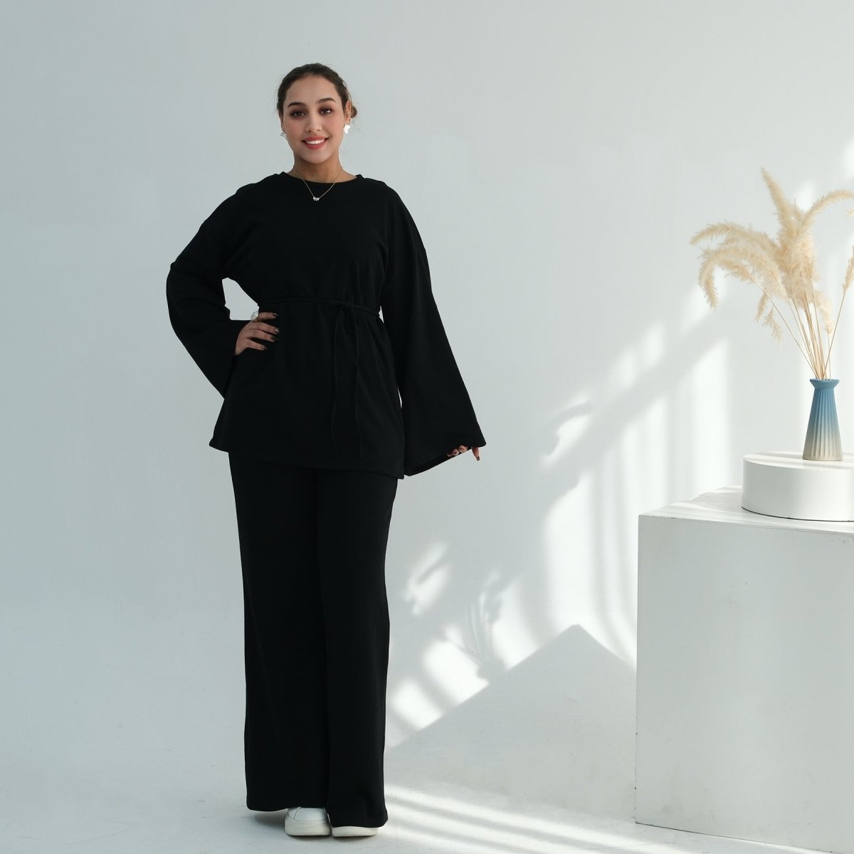 Layered styling of cotton batwing top worn over wide-leg trousers